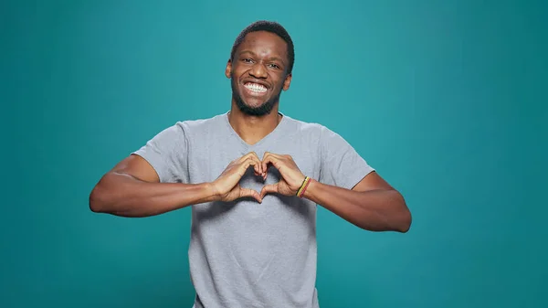 Smiling man making heart shape sign with hands in front of camera — Stock Photo, Image