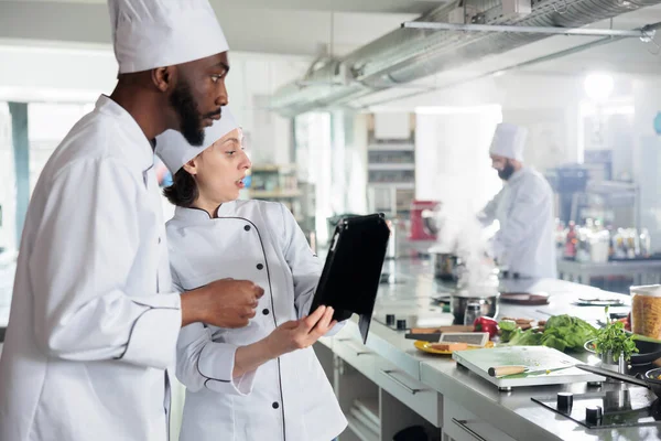 Gourmet expertos en cocina con tableta moderna en busca de ideas plato de servicio de cena en Internet. —  Fotos de Stock