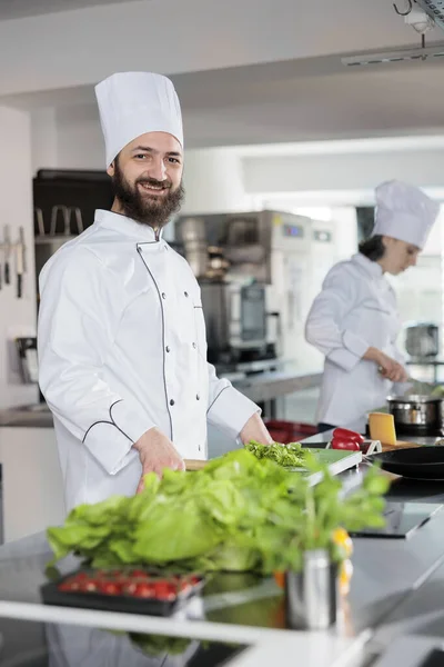 Retrato del chef jefe feliz vistiendo uniforme de cocina, de pie en la cocina profesional del restaurante —  Fotos de Stock