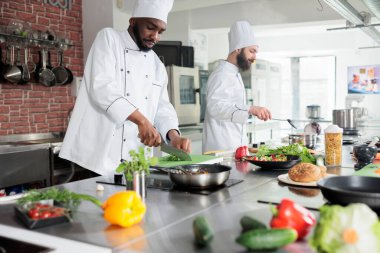 Yemek endüstrisi Afro-Amerikan işçisi, gurme yemeği pişirirken taze organik otlar doğradı..