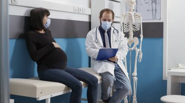 Hekim ve hamile kadın kabinede danışmanlık yapıyor.