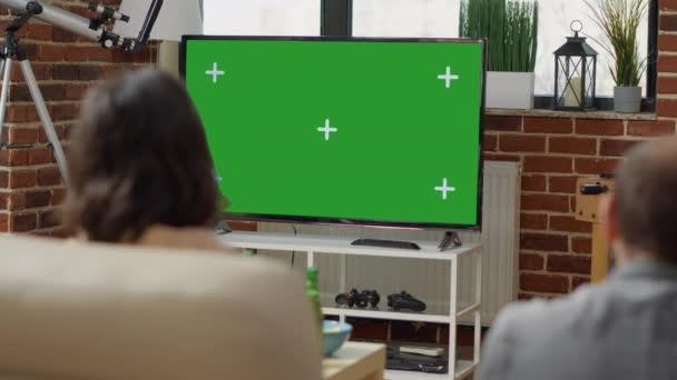 Young people on sofa looking at television with green screen — Stock Video