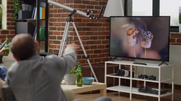 Happy people watching movie on television with beer and snacks — Stock videók