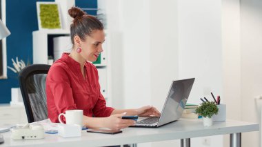 Ofis çalışanı laptopta kredi kartıyla ödeme yapıyor.