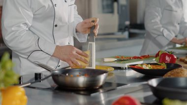 Profesyonel şef tabağa doğranmış peynir eklemek için rende kullanıyor.