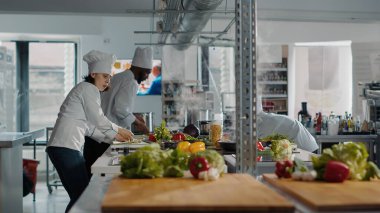 Üniformalı kadın mutfak sobasında lezzetli yemekler pişiriyor.