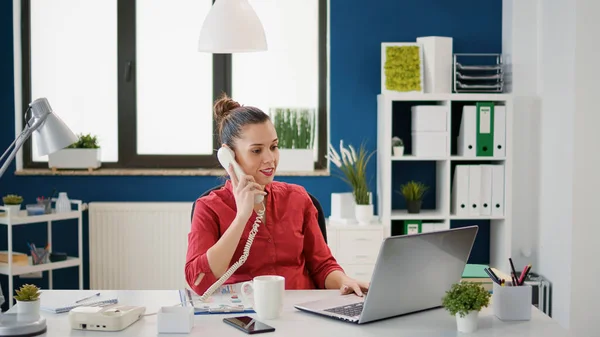 Vrouwelijke secretaris met behulp van vaste telefoon op het werk van het bedrijf — Stockfoto