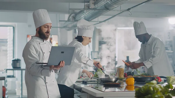 Hombre y mujer usando el ordenador portátil para cocinar la receta de alimentos en la cocina —  Fotos de Stock