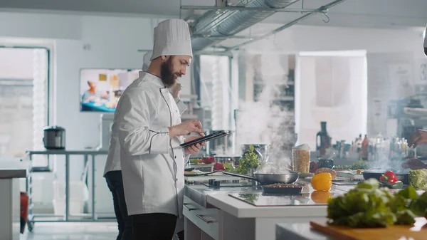 Cocinero masculino analizando receta culinaria en la tableta digital en la cocina —  Fotos de Stock