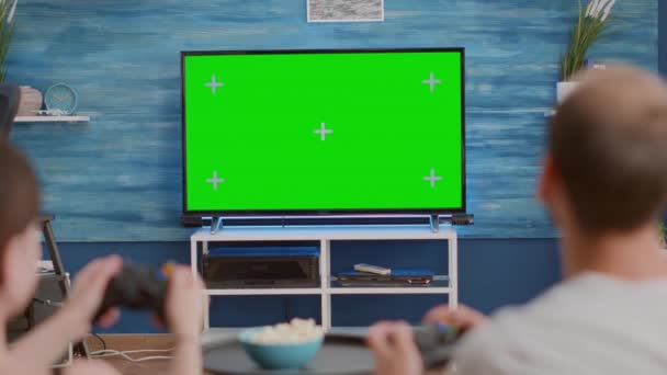 Gros plan de couple tenant des contrôleurs jouant à des jeux de console d'actine sur l'écran vert tv assis sur le canapé — Video