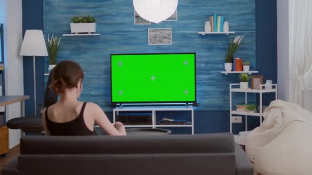 Young woman eating popcorn while relaxing watching movie on green screen television — Video