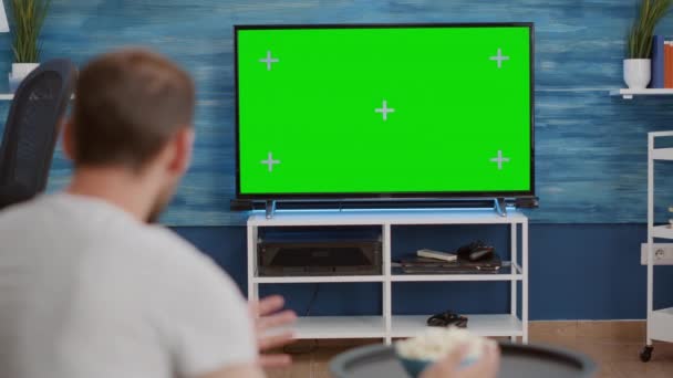 Over shoulder view of sports fan watching game on green screen tv mockup encouraging favourite team — Stock video