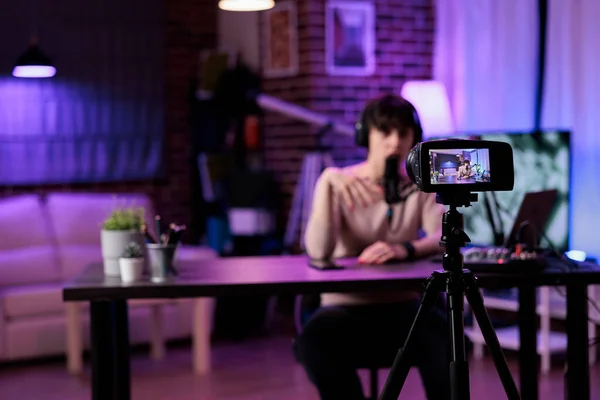 Caucasian woman recording online podcast discussion on camera, vlogging live channel content. Female influencer filming video conversation with audience, using streaming equipment.