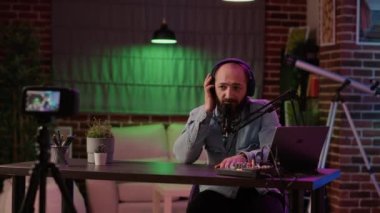 Caucasian male influencer filming video with podcast equipment in studio recording online vlog using digital camera