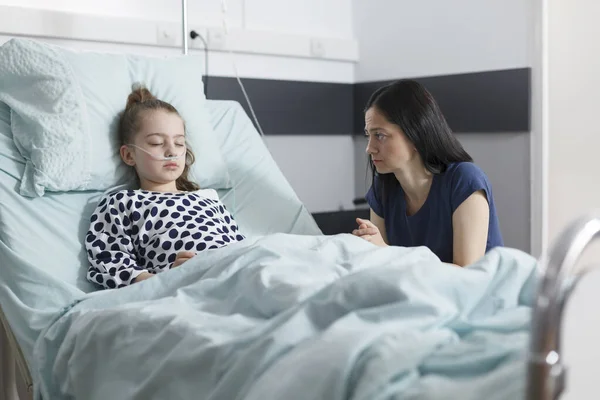 Thoughtful worried sad woman looking at sleeping ill hospitalized little girl —  Fotos de Stock