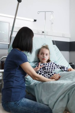 Düşünceli genç anne, sağlıksız küçük kızıyla konuşurken duygusal destek teklif ediyor..