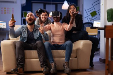 Diverse group of workmates playing video games with vr headset