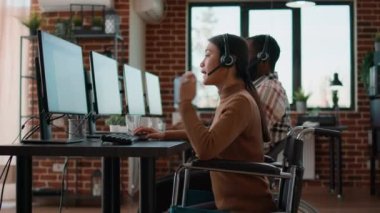 Female worker in wheelchair talking on phone helpline at call center