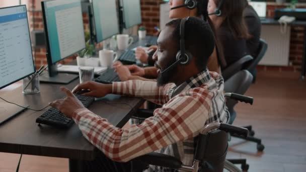Irodai dolgozó fogyatékossággal, fejhallgatóval beszél az ügyfelekkel — Stock videók