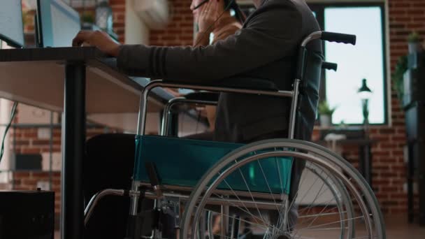 Tekerlekli sandalyedeki Afrikalı Amerikalı adam telefon hattında kulaklık kullanıyor. — Stok video