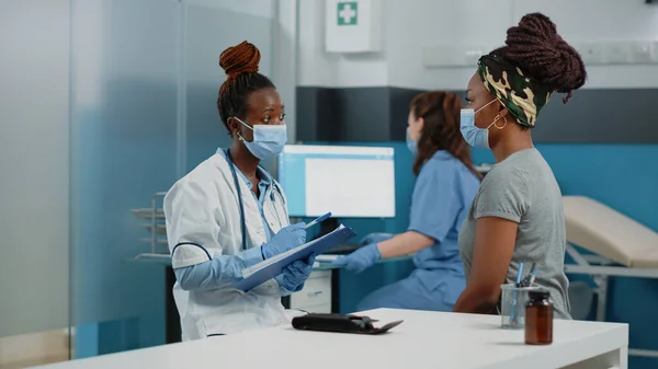 Medico e paziente con maschere facciali che parlano di malattia — Foto Stock