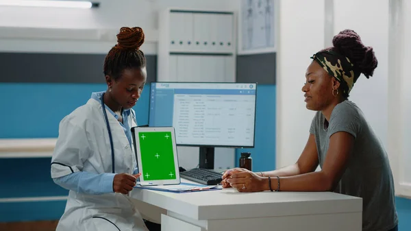 Sanitäter zeigt auf Tablet mit grünem Bildschirm und spricht mit Patient — Stockfoto