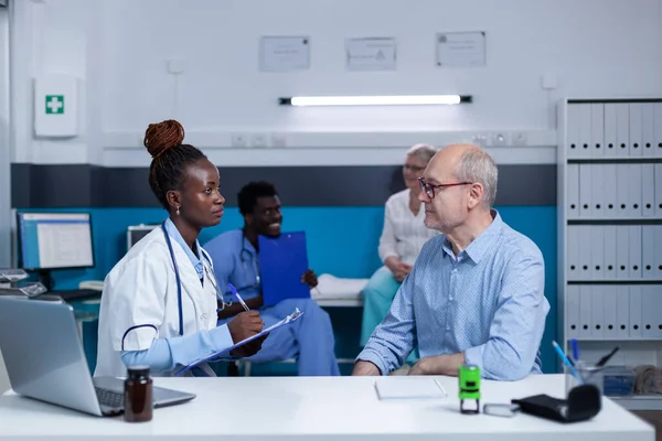 Médecin de l'hôpital écrit les symptômes de la maladie des patients âgés malades — Photo