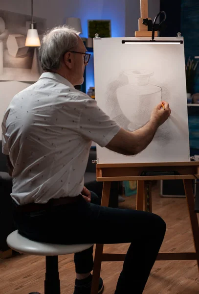Anciano asistiendo a taller de arte nocturno haciendo dibujo original de jarrón usando lápiz hb —  Fotos de Stock