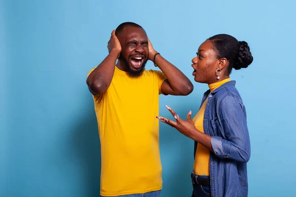 Woman yelling at man covering his ears to stop argument