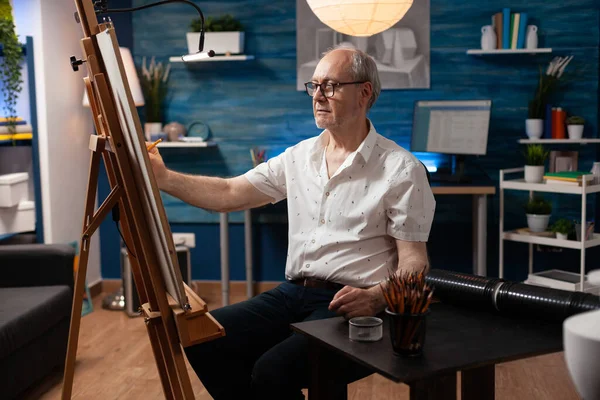 Emekli yetenekli yaşlı bir adamın portresi keskin kalemle resim sehpasında yaratıcı bir başyapıt yapıyor.