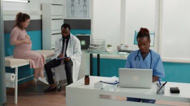 Randevu sırasında kabinede dizüstü bilgisayarda çalışan tıbbi asistan