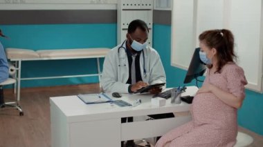 Check-up randevusunda dijital tablet kullanan erkek doğum uzmanı