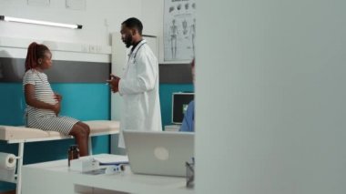 Afrikalı Amerikalı doktor hamile kadına bir şişe hap veriyor.