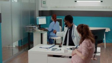 Sağlık kontrolünde Afrika kökenli Amerikalı doktor ve yüz maskeli bir kadın var.