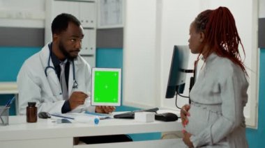 Erkek doğum uzmanı yeşil ekranlı dijital tablet gösteriyor