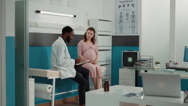 Male physician taking notes on checkup files at consultation — Stock videók