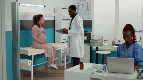 General practitioner attending consultation with pregnant woman — Vídeo de Stock