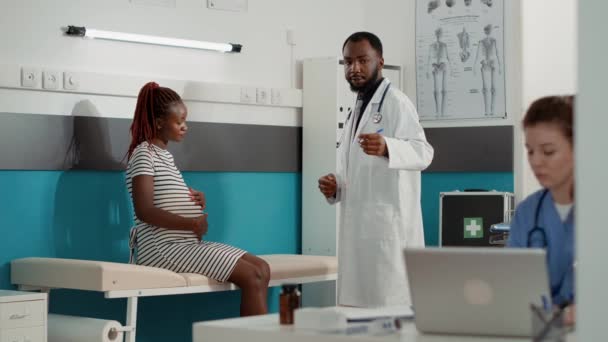 African american doctor giving prescription pills to pregnant patient — Wideo stockowe