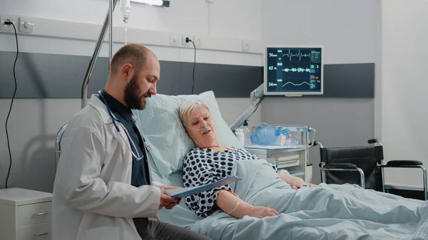 Лікар і медсестра проводять консультацію для хворого пацієнта в ліжку — стокове фото