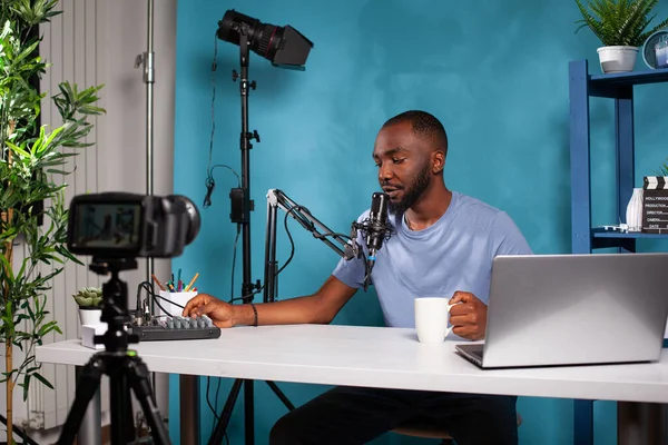 İçerik oluşturucu online sabah programında takipçilerle konuşuyor. Karıştırıcı konsolunun sesini ayarlıyor.