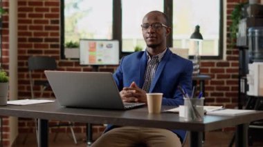 Ofis masasında oturan Afrikalı Amerikan işçisinin portresi.