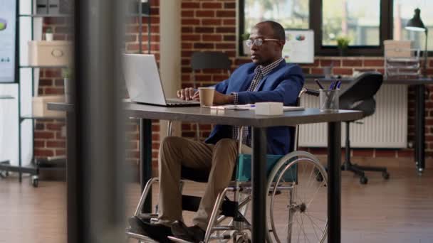 Project manager creating report on laptop in disability friendly office — Videoclip de stoc