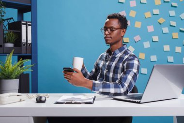 Marketing company businessman browsing social media on mobile smartphone while having a cup of coffee.