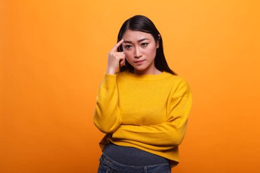 Ciddi düşünceli kadın turuncu arka plan üzerinde derin düşüncelere odaklanmış..