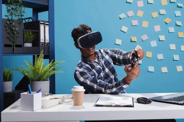Speelse kantoorpersoon die virtual reality-technologie-headset draagt terwijl hij moderne controller gebruikt om casual videospelletjes op het werk te spelen. — Stockfoto