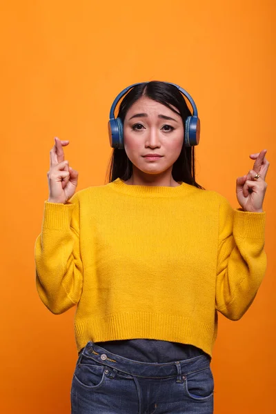 Anxious stressed asian woman having crossed fingers before job interview on orange background — Fotografia de Stock