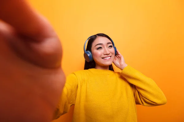 Confident beautiful carefree influencer wearing headphones and yellow sweater taking selfie photo — Fotografia de Stock