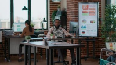 Young man helping businesswoman in wheelchair to work at desk