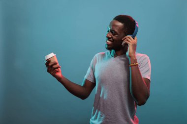 Kaygısız insan kulaklıkla ve kahveyle mp3 müziğinin keyfini çıkarıyor.