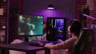 Handheld shot of gamer girl celebrating winning first place in action space game while man is playing first person shooter